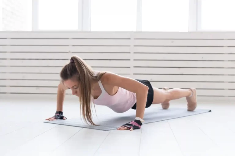 Una mujer realiza flexiones en una colchoneta sobre el suelo en una clase de Tonificación.