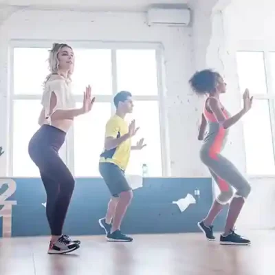 Dos mujeres y un hombre realizan ejercicios de baile en una clase de Zumba