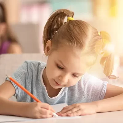 Una niña borra algo escrito en una página con la goma de borrar de su lápiz, en una clase de euskera e inglés
